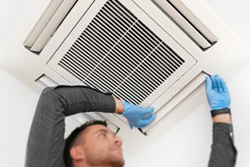 A person in gloves is servicing an AC repair for a ceiling cassette.