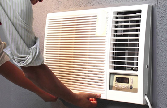 A person is adjusting the AC on a wall-mounted window.
